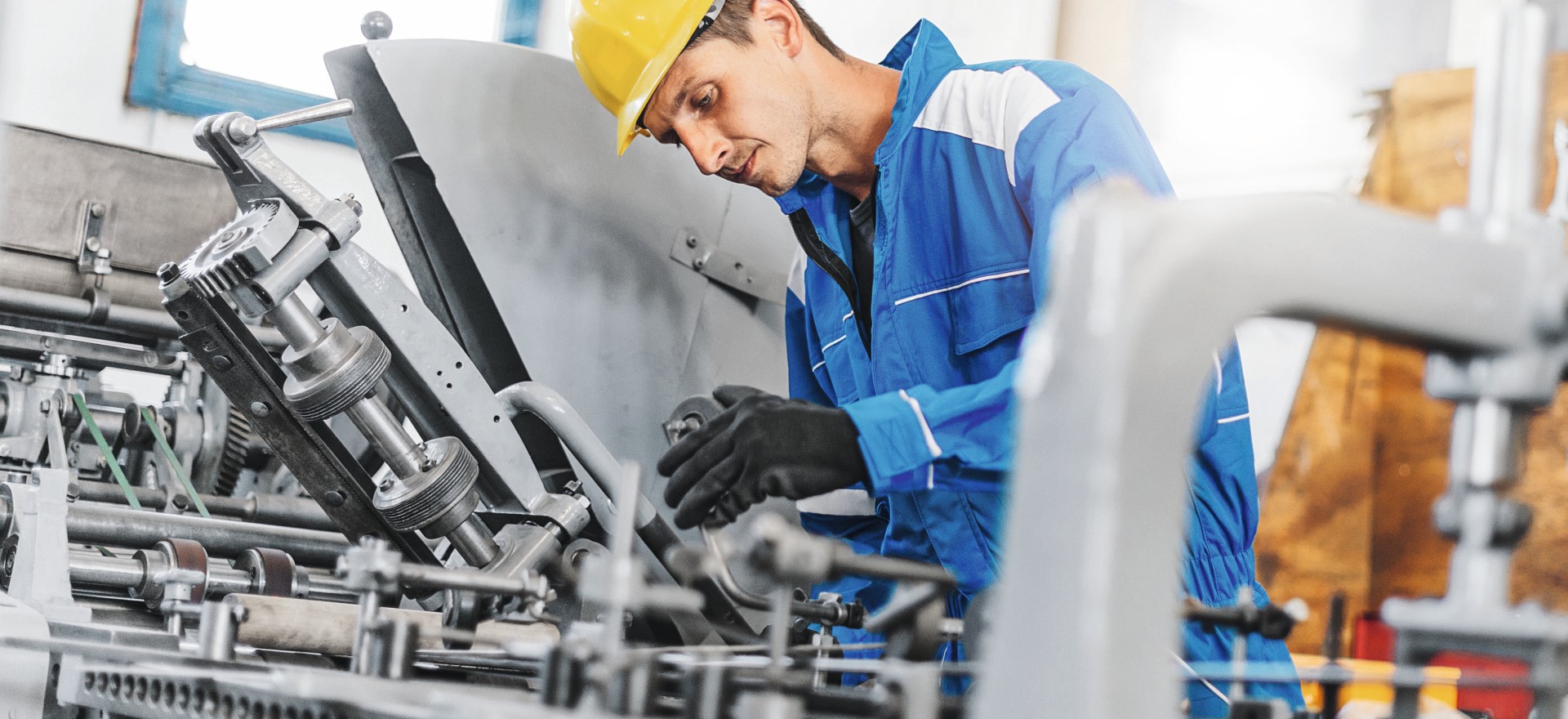 Repairman taking care of broken machinery Blue collar worker or engineer working in industrial production plant, dealing with metal processing, hydraulic machinery, production lines and other pprocessing industry machines. Image taken in Serbia, Europe.